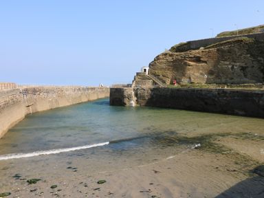 A small harbor with stone walls and clear water next to rocky cliffs at Apple Tree Bungalow in Lanner