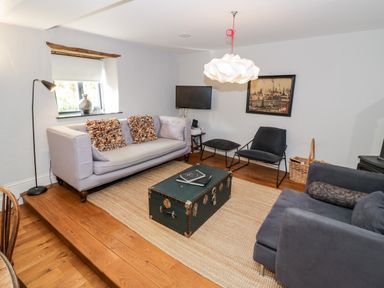 A living room with sofas a coffee table a TV and a wall picture at The Old Stables in Chipping Campden