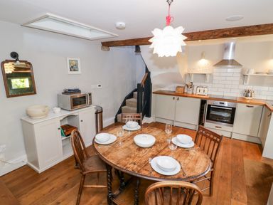 A kitchen with a round wooden dining table set with bowls and glasses at The Old Stables in Chipping Campden