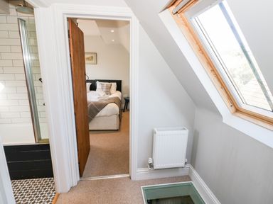A hallway with a skylight window radiator and a bedroom visible through an open door at The Old Stables in Chipping Campden