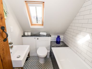 A bathroom with a sink toilet bathtub skylight and blue vase at The Old Stables in Chipping Campden