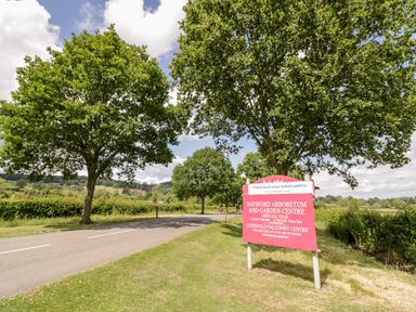 A road with trees and a sign for Batsford Arboretum and Garden Centre by the roadside at The Old Stables in Chipping Campden