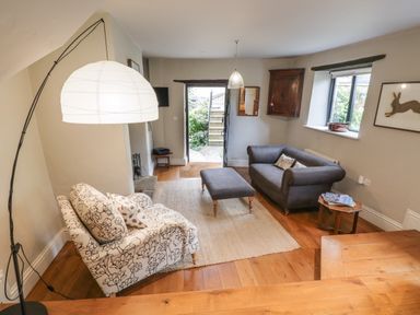 A living room with two sofas a coffee table lamp and a door leading outside at The Old Brewhouse in Chipping Campden
