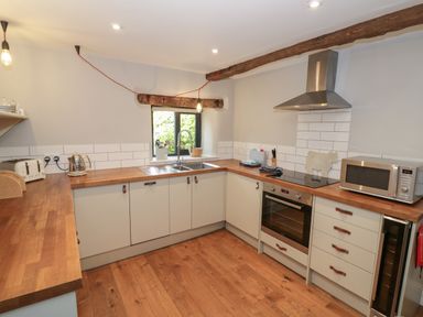 A kitchen with wooden countertops white cabinets stainless steel oven microwave and toaster at The Old Brewhouse in Chipping Campden