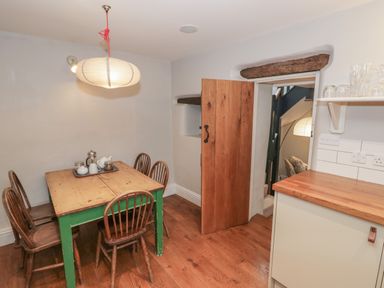 A dining area with a wooden table and chairs and a hanging light at The Old Brewhouse in Chipping Campden