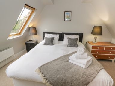 A bedroom with a double bed two lamps a window pillows and folded towels on the bed at The Old Brewhouse in Chipping Campden