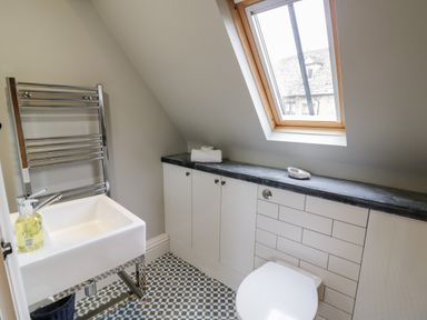 A small bathroom with a sink toilet towel rack cabinet under a slanted roof window at The Old Brewhouse in Chipping Campden