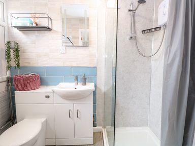 A bathroom with a toilet sink mirror shower and storage at 72 in Hemsby