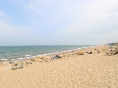 A sandy beach with rocks and people near the shore at 72 in Hemsby