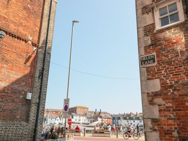 A street view with people walking and cycling near a marina with boats and houses in the background at Helen Lane