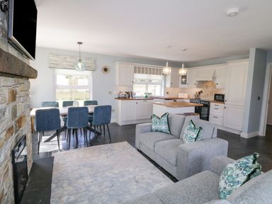 An open living room and kitchen with grey sofas and blue chairs at The Haven in Falcarragh County Donegal