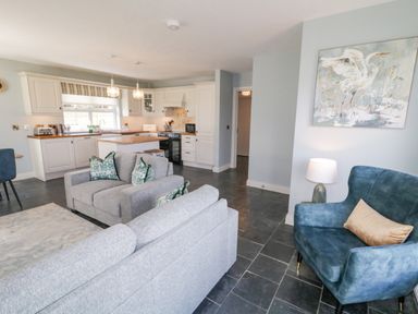 An open plan kitchen and living area with grey sofas and blue armchair at The Haven in Falcarragh County Donegal