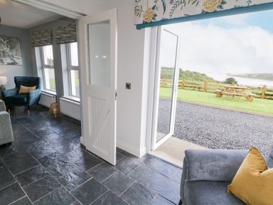 A room with slate tile flooring a blue armchair and a door open to a garden with picnic table at The Haven in Falcarragh County Donegal