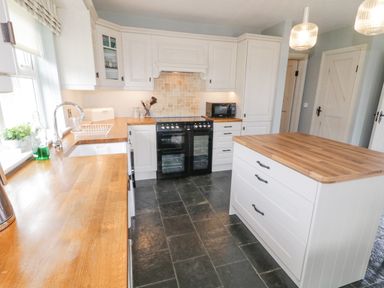 A kitchen with wooden countertops white cabinets a black oven and a kitchen island at The Haven in Falcarragh County Donegal