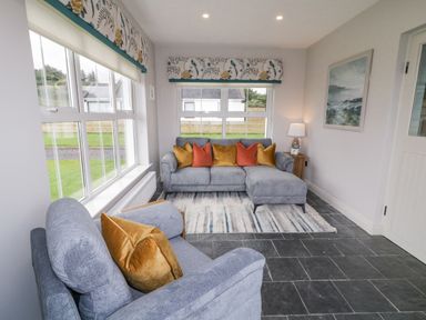 A living room with grey sofas and colorful cushions near windows with floral valances at The Haven in Falcarragh County Donegal