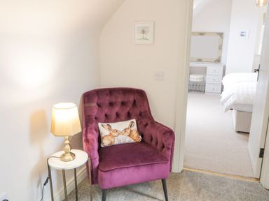 A purple armchair with a rabbit cushion next to a small round table with a lamp and a bedroom visible through an open door at The Haven in Falcarragh County Donegal