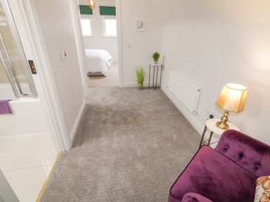A hallway with a purple chair a lamp on a small table plants and carpet at The Haven in Falcarragh County Donegal