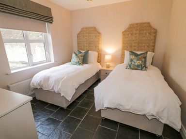 A bedroom with two single beds with patterned headboards and floral pillows and a bedside table with a lamp at The Haven in Falcarragh County Donegal