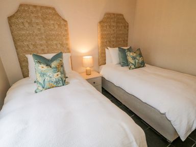A bedroom with two single beds with patterned headboards and a nightstand with a lamp between them at The Haven in Falcarragh County Donegal