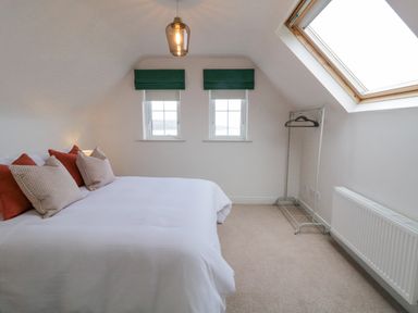 A bedroom with a bed with pillows two windows a skylight and a clothes rack at The Haven in Falcarragh County Donegal