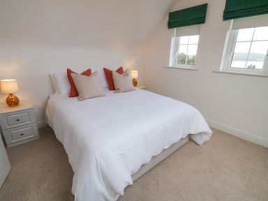A bedroom with a bed white bedding two bedside tables with lamps and two windows with green blinds at The Haven in Falcarragh County Donegal