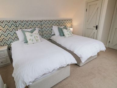 A bedroom with two single beds with patterned headboards and white bedding at The Haven in Falcarragh County Donegal