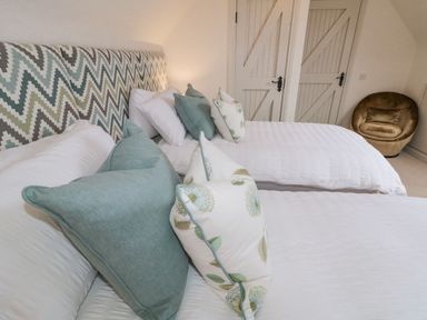 A bedroom with two beds with patterned headboards decorative pillows and a round chair at The Haven Falcarragh County Donegal