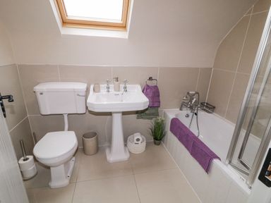 A bathroom with a toilet sink bathtub skylight and purple towels at The Haven in Falcarragh County Donegal
