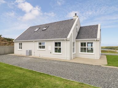 A single-story house with a sloped roof and multiple windows beside a gravel driveway at The Haven in Falcarragh County Donegal