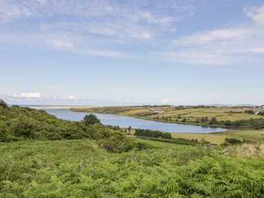 A landscape with a river flowing through fields and hills under a partly cloudy sky at The Haven in Falcarragh County Donegal