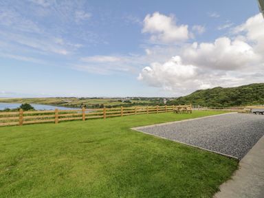 A grassy yard with a wooden fence and picnic table overlooking a river and hills at The Haven in Falcarragh County Donegal