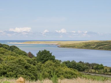 A coastal landscape with a body of water surrounded by green hills and trees at The Haven in Falcarragh County Donegal