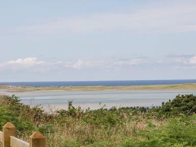 A coastal landscape with grassy foreground a body of water and the sea at The Haven in Falcarragh County Donegal
