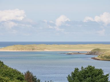 A coastal scene with a body of water trees a small pier and grassy hills at The Haven in Falcarragh County Donegal