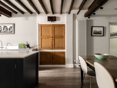 A kitchen and dining area with wooden cabinets and a black island at Fron Dderw in Bala