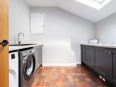 A utility room with a washing machine, dryer, sink, and cabinets at Fron Dderw in Bala