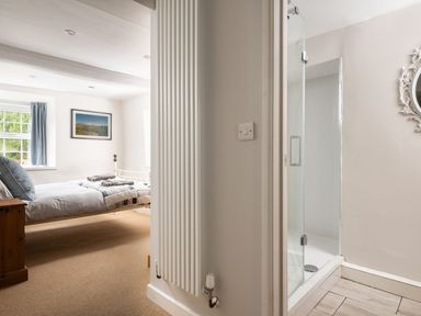 A bedroom with a bed and windows next to a bathroom with a shower at Fron Dderw in Bala