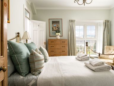 A bedroom with a bed and pillows a chest of drawers and a window with curtains at Fron Dderw Bala