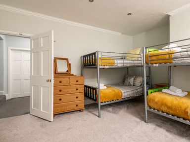 A bedroom with two sets of metal bunk beds and a wooden chest of drawers with a mirror at Fron Dderw Bala