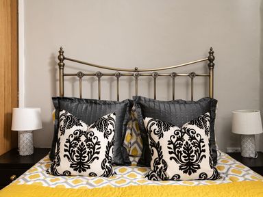 A bed with decorative pillows and a metal headboard with two bedside tables and lamps at Fron Dderw Bala