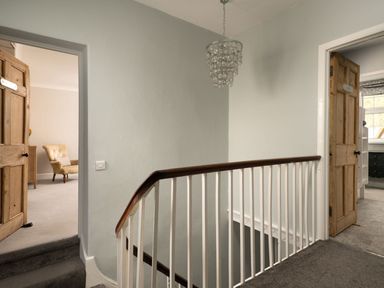 A landing area with carpeted stairs and two wooden doors leading to rooms at Fron Dderw in Bala