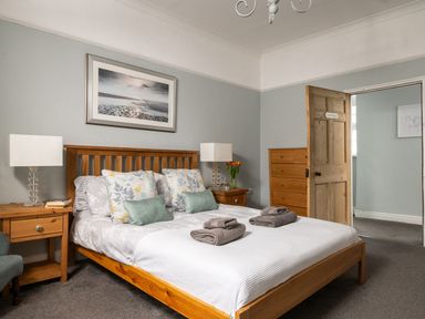 A bedroom with a wooden bed frame and bedside tables with lamps at Fron Dderw in Bala