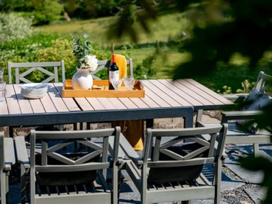 An outdoor dining table with plates a bottle glasses and a vase with flowers at Fron Dderw Bala