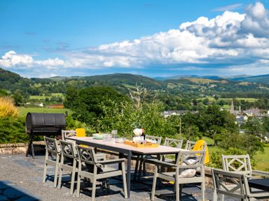 An outdoor dining table with chairs and a barbecue grill with a countryside view at Fron Dderw Bala