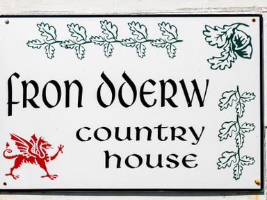 A sign with the text Fron Dderw country house decorated with green leaf designs and a red dragon at Fron Dderw in Bala