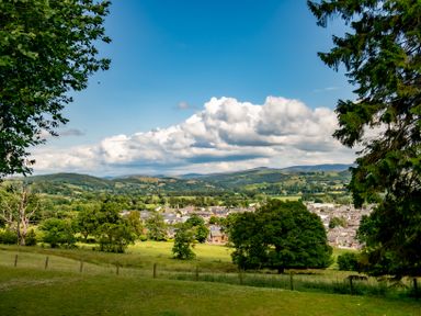 A landscape view of a town with trees and grassy fields in the foreground and hills in the background at Fron Dderw in Bala