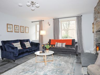 A living room with two sofas a round coffee table and a stone fireplace at Glyn Awel Nant Gwynant near Beddgelert
