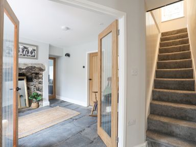 A hallway with stone floor a rug an open wooden door a staircase with carpet and a wooden door at Glyn Awel in Nant Gwynant near Beddgelert