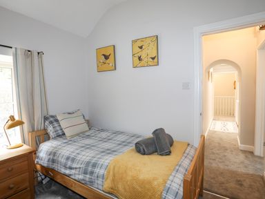 A bedroom with a single bed wooden nightstand and a lamp at Glyn Awel in Nant Gwynant near Beddgelert