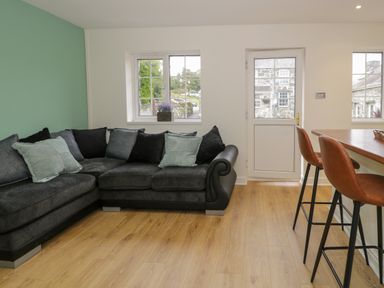 A living room with a gray sectional sofa and bar stools at Bwythyn Yr Wyddfa in Llanberis